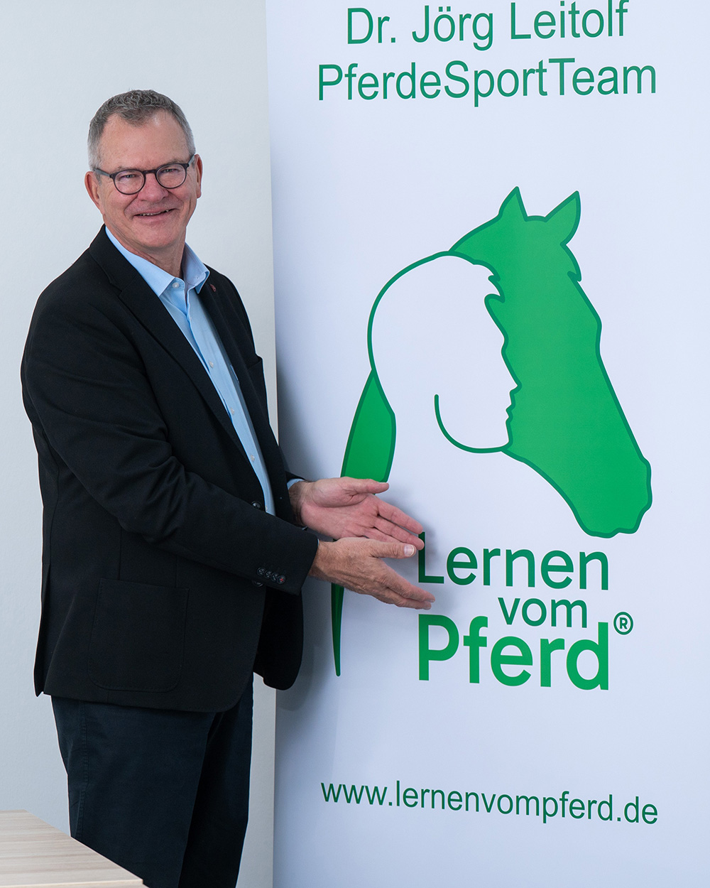 Jörg zeigt auf das Logo von Lernen vom Pferd